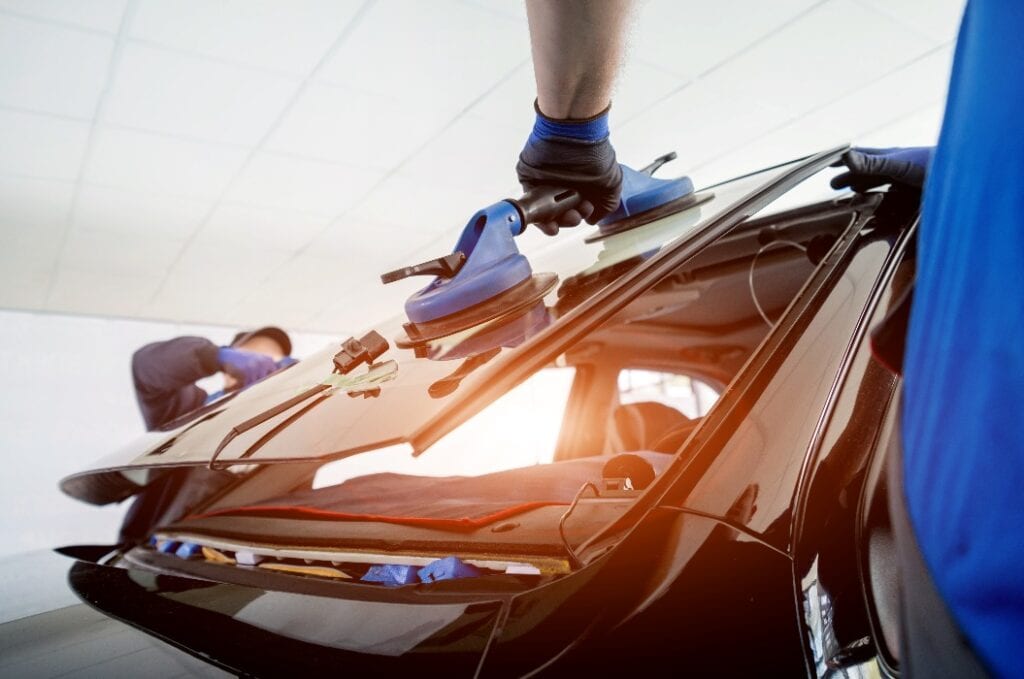 Automobilspezialist ersetzt die Windschutzscheibe eines Autos in einer Autowerkstatt.