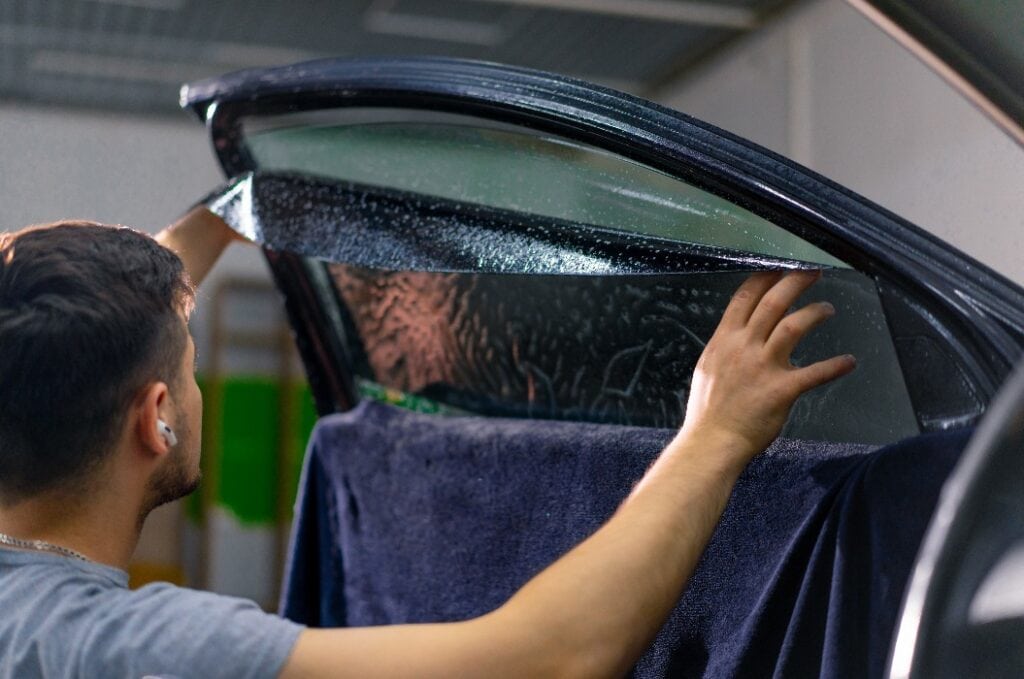 Männliche Auto-Service-Arbeiter Kleber Fenster Tönung in Luxus Auto Detaillierung Autoreparatur das Konzept der Liebe für Autos und ein Schutz